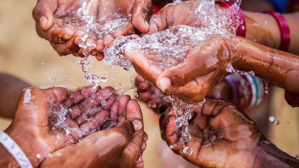 A group of hands cupping water flowing from a tap