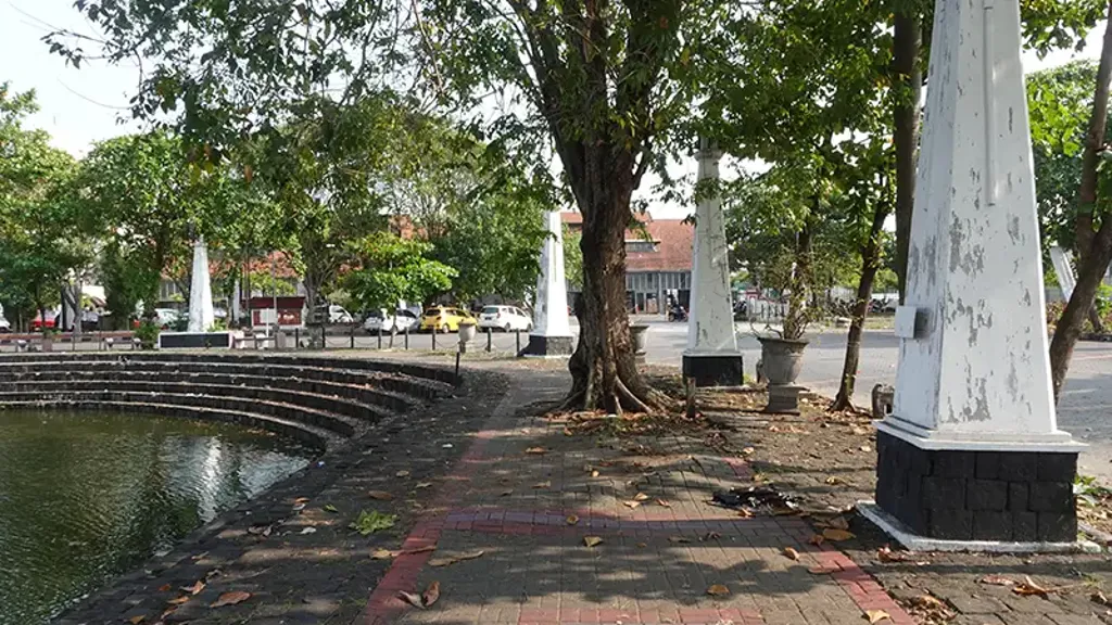 A brick walkway with trees and a fountain