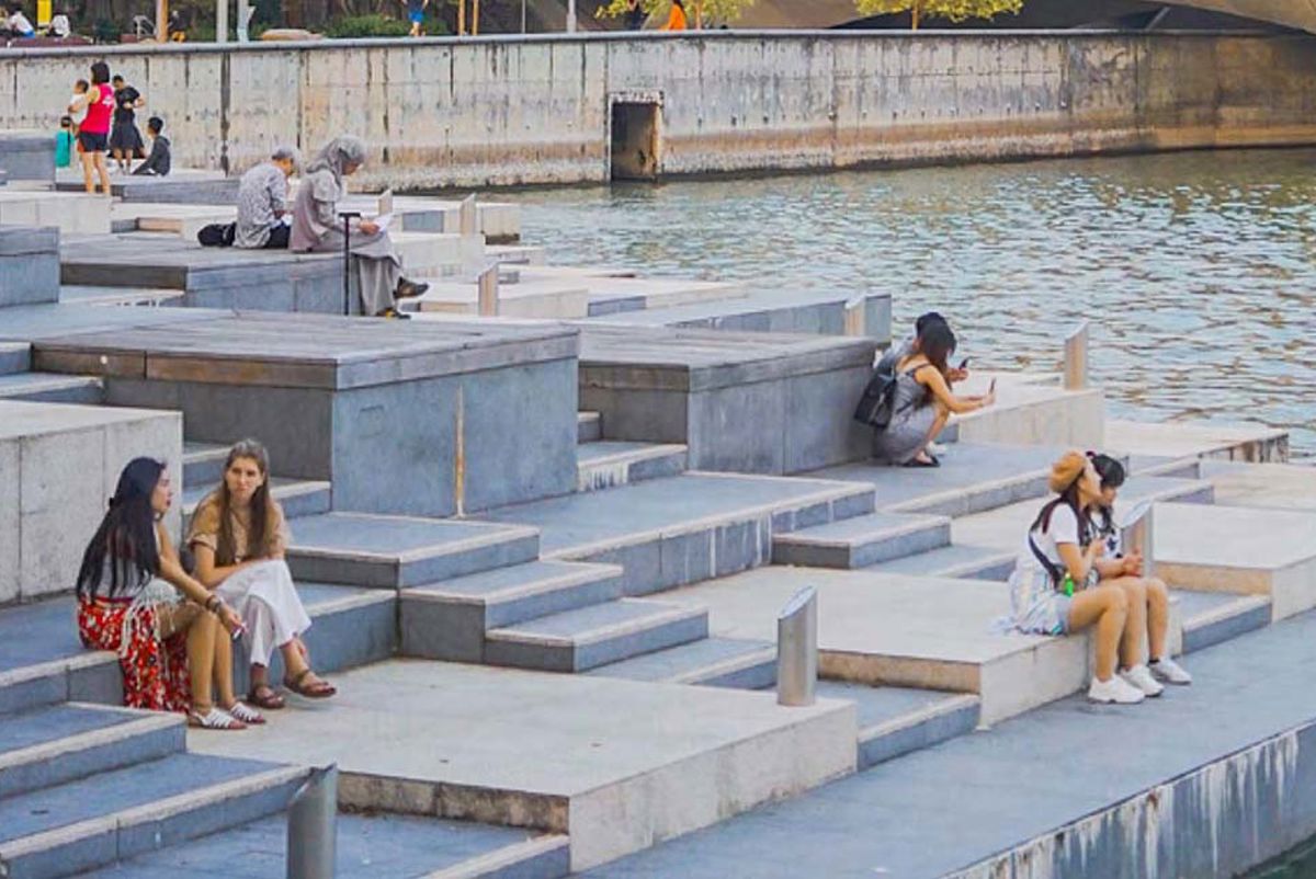 Women sitting by a body of water in a city