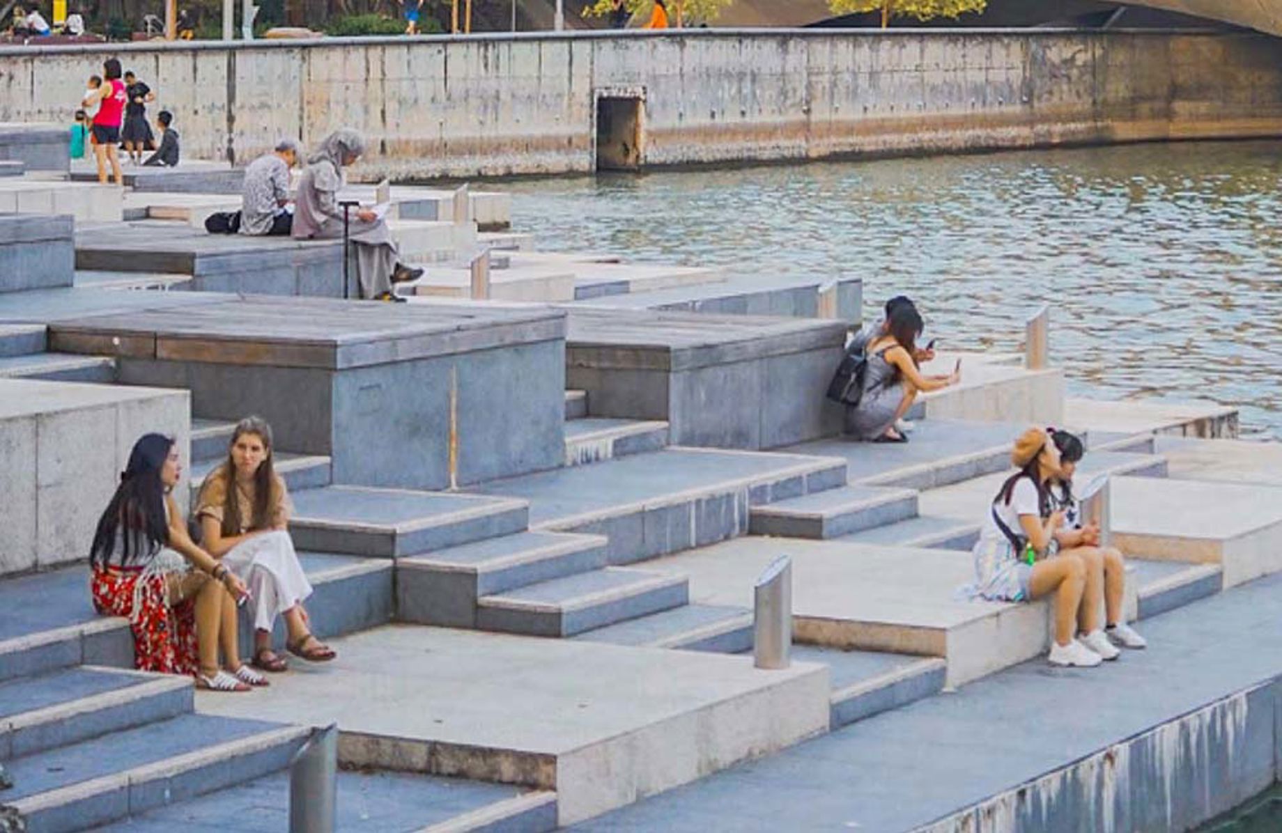 Women sitting by a body of water in a city