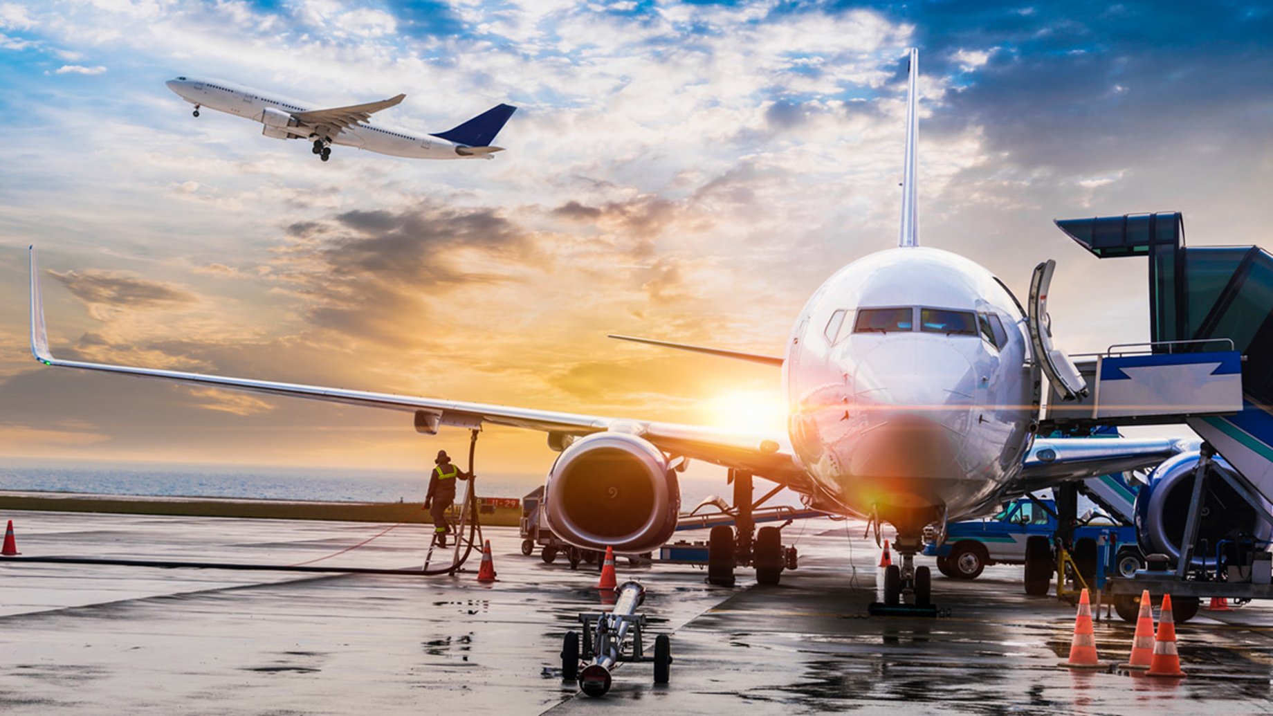 Airplane at an airport with a plane taking off in the background