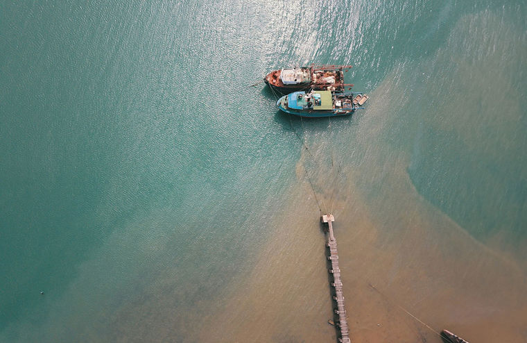 Aerial view looking down on the sea with ships off a pier