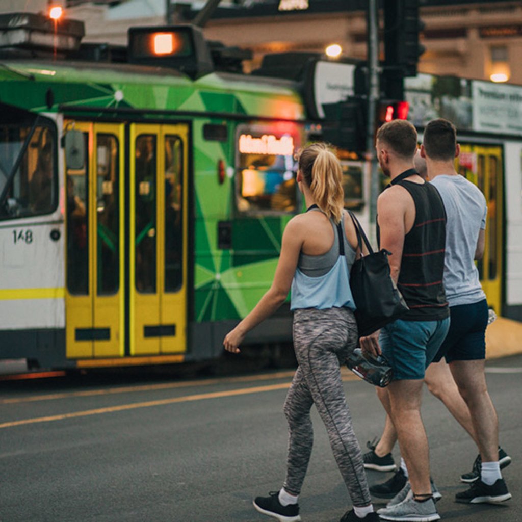 People walking on a street with a tram in the background