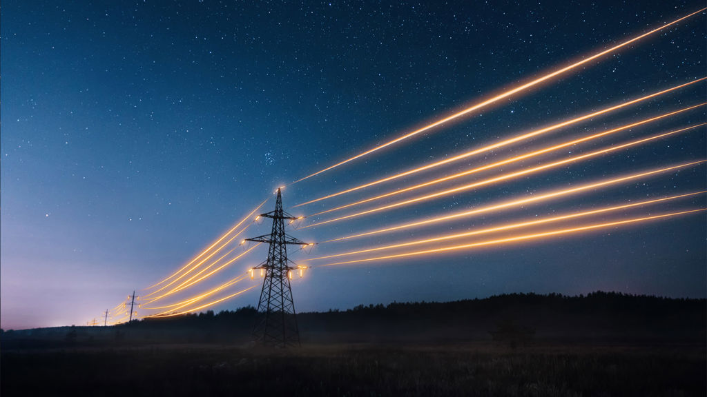 Electricity transmission towers with orange glowing wires in the night sky