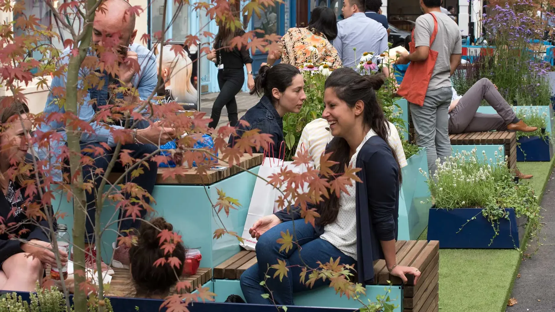 People chatting whilst seated on a parklet