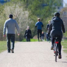 A person cycling and people walking on a path