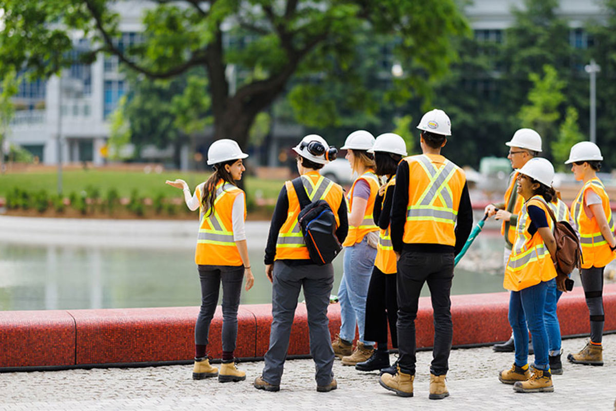 Several people wearing site safety gear visit an urban park